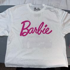 White T-Shirt With Pink Barbie Letters And Graphics On Back Size:M Raw Cut Off Hem White Text Print Crew Neck Top, Basic White Tops With Letter Print, Basic White Tops With Screen Print, White Slogan Crew Neck Top, White Print Logo Graphic Tee Shirt, Trendy White Tops With Logo Print, White Logo Print Graphic Tee, Casual White Slogan Shirt, Casual White Shirt With Slogan