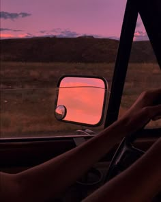 a person is sitting in the driver's seat of a car as the sun sets