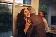 two people hugging each other in front of a window