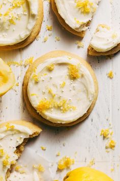 lemon cookies with white frosting and sprinkles next to an orange slice