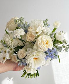 a hand holding a bouquet of white and blue flowers