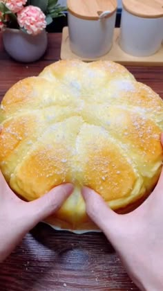 a person holding a pie on top of a wooden table