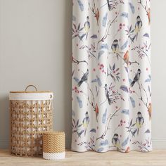 a curtain with birds on it next to a wicker basket and plant in the corner