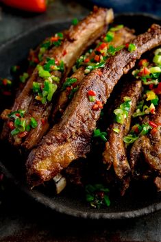 a black plate topped with meat and veggies