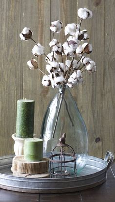 a vase filled with white flowers sitting on top of a wooden table next to a thread spool