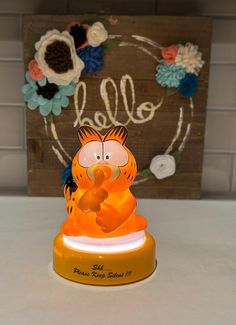 an orange and yellow figurine sitting on top of a white table next to a wooden sign