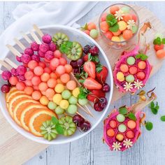 a bowl filled with fruit on top of a wooden cutting board