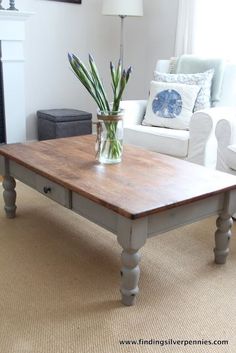 a coffee table with flowers in a vase on it and a white couch behind it