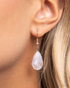 a close up of a woman's ear wearing earrings with white stones on them