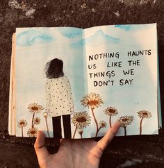 a hand holding an open book with the words nothing wants us like the things we don't say