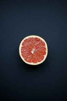 a grapefruit cut in half on a black surface