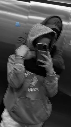 a person wearing a hoodie taking a selfie in front of a metal object