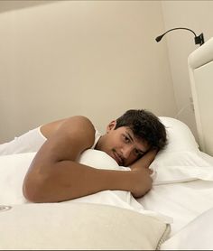 a man laying on top of a bed under a white blanket