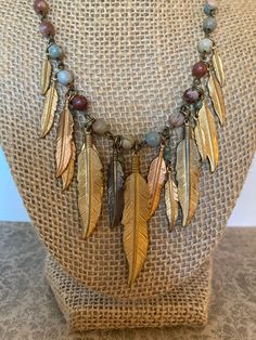 Brass feathers in various states of patina dangle from an 18 inch beaded necklace.  Beautiful autumn tones.  Brass lobster clasp.  Handcrafted and one of a kind. Multicolor Feather Jewelry For Festivals, Adjustable Bohemian Necklaces With Feathers, Bohemian Brown Necklace With Dangling Beads, Bohemian Dangle Copper Necklace, Bohemian Copper Dangle Necklaces, Bohemian Brown Feather Jewelry, Handmade Bohemian Bronze Charm Necklaces, Handmade Bronze Bohemian Charm Necklaces, Handmade Bronze Bohemian Charm Necklace