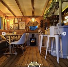 the inside of a restaurant with wooden floors and walls covered in wood planks, white bar stools