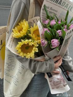 a woman is holding a bouquet of sunflowers in her hands while walking down the street