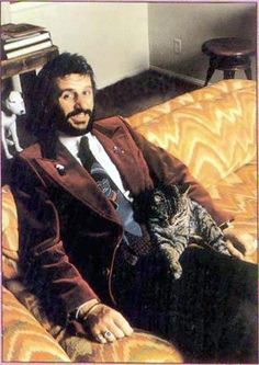 a man sitting on top of a couch holding a cat