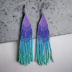 Handmade Seed Bead Beaded Earrings In Purple, Blue, And Turquoise 4.75” Long Dimensions 4.75”L X .75”W These Handmade Seed Bead Earrings Are A Stunning Combination Of Purple And Blue Beads. The Intricate Design And Vibrant Colors Make Them A Perfect Accessory To Add A Pop Of Color To Any Outfit. With Their Lightweight Feel And Comfortable Fit, These Beaded Earrings Are Ideal For Everyday Wear Or Special Occasions. The Attention To Detail And Craftsmanship Is Evident In Every Bead, Making Them A Blue Dangle Beaded Necklace With Tiny Beads, Purple Seed Bead Earrings, Purple Faceted Beaded Round Earrings, Purple Faceted Beaded Earrings, Bohemian Purple Beaded Earrings For Beach, Purple Dangle Beaded Earrings With Spacer Beads, Handmade Purple Beaded Earrings For Beach, Purple Beaded Earrings With Colorful Beads, Adjustable Purple Beaded Earrings With Colorful Beads