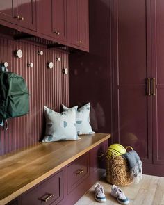 a wooden bench sitting in the middle of a room with purple cabinets and pillows on it