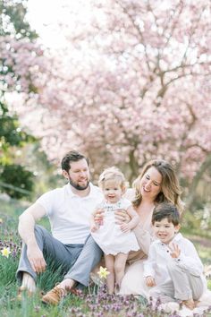 a family sitting in the grass with pink flowers