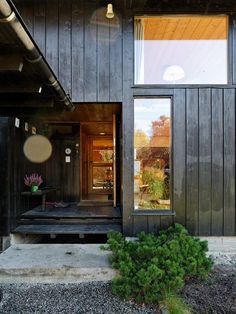 the front door is open and there are plants in the garden outside it on the side of the house