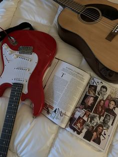 an open book and guitar sit on a bed next to it's electric guitar