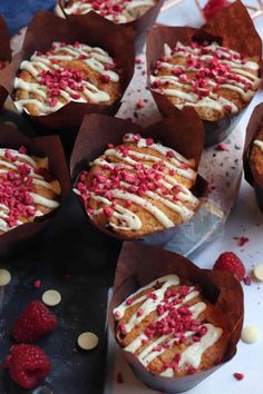 some cupcakes with white frosting and raspberries