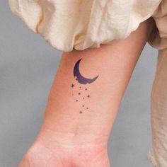 a woman's arm with a small crescent and stars tattoo on it