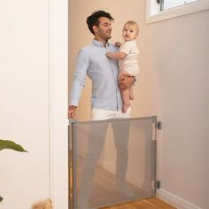 a man holding a baby in his arms while standing next to an open door with a screen on it