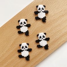 four panda bear bead magnets sitting on top of a wooden board