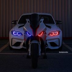 two white sports cars parked next to each other in a parking lot with their lights on