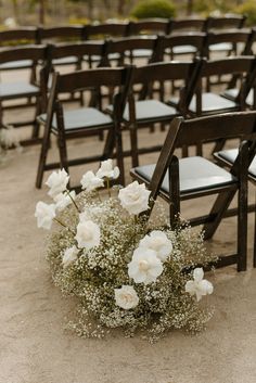 an arrangement of white flowers and baby's breath sits in the middle of rows of empty chairs