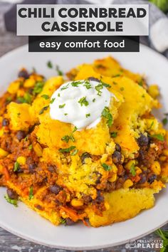 chili cornbread casserole on a white plate with sour cream in the middle