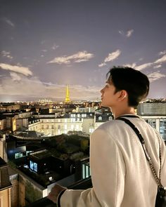 a man standing on top of a tall building next to a cityscape with the eiffel tower in the background