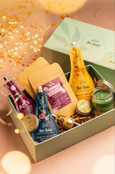 an open gift box filled with condiments and snacks on a pink tablecloth