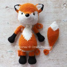 an orange and white knitted fox doll next to it's tail with scissors