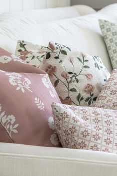 pillows on a white couch with pink and green florals in the backround