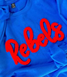 Rebs Pullover embroidered with chenille Royal with Red Chenille Please view other images for sizing and styling guides. *We use only the highest quality Heavy Blend Gildan Unisex Sweatshirts Laundering: wash inside out and line dry for best results. College Red Tops With Embroidered Text, Red College Tops With Embroidered Text, Red Embroidered Text College Tops, Red College Top With Embroidered Text, Red Embroidered Crew Tops, Red Embroidered Tops For Fall, Blue Sweater With Letter Embroidery For Fall, Blue Sweater With Embroidered Text For Fall, Blue Fall Sweater With Letter Embroidery