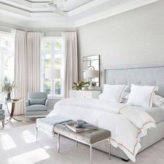 a large white bed sitting in a bedroom next to a window