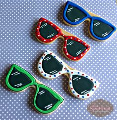 decorated cookies with sunglasses and polka dots on a blue tablecloth, ready to be eaten