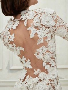 the back of a woman's wedding dress with white lace and flowers on it