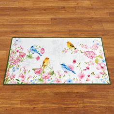 a rug with birds and flowers on it in the middle of a wood flooring area