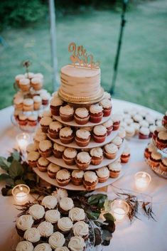 a wedding cake and cupcakes on a table