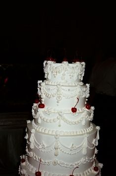 a large white wedding cake with cherries on it