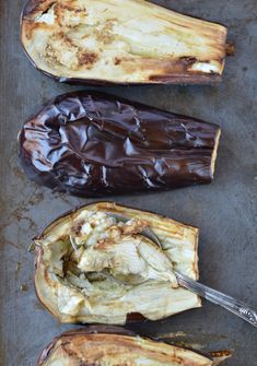 three eggplant halves on a baking sheet with a spatula