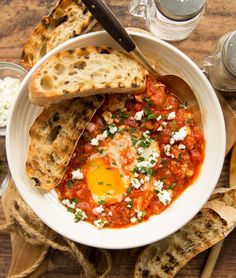 a white bowl filled with food next to bread