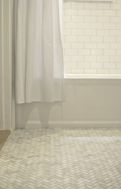 a bathroom with a white shower curtain next to a window