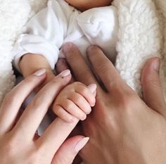 a woman holding a baby wrapped in a blanket with her hands on top of it