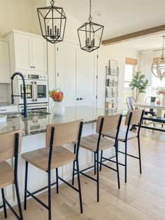 a kitchen with white cabinets and wooden chairs in front of the counter top, along with an island