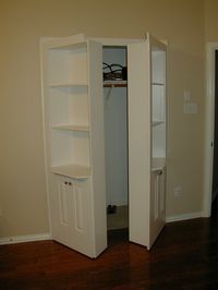 an empty room with a white bookcase in the corner and a door to another room